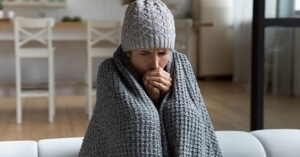 photo of a woman bundled in blankets in her home